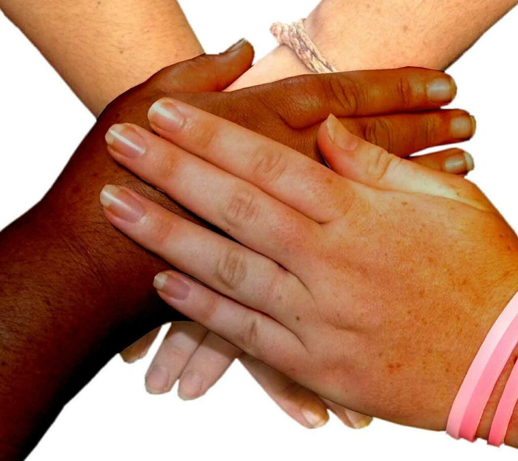 Hands of all colors, holding and resting on top of each other.
